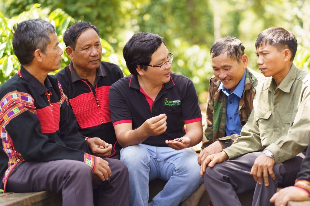 Cán bộ hỗ trợ nông nghiệp của Nestlé Việt Nam chia sẻ kinh nghiệm canh tác cà phê bền vững cho các hộ nông dân tham gia chương trình NCP