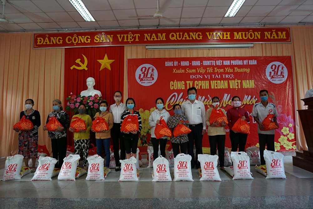 Đại diện công ty Vedan Việt Nam ( áo trắng từ phải qua ) cùng đại diện UBND phường Mỹ Xuân, thị xã Phú Mỹ, BRVT trao quà tết cho bà con tại địa phương.